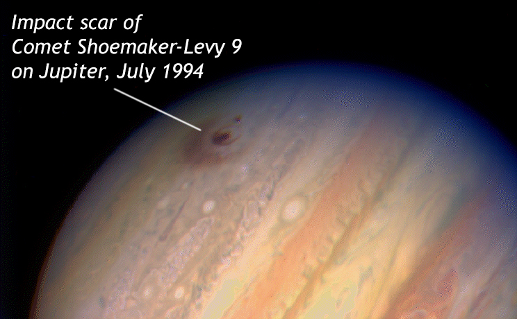 A photograph (through a telescope) showing a prominent red/brown concentric-ring shaped "scar" on Jupiter's atmosphere where Comet Shoemaker-Levy 9 impacted it.