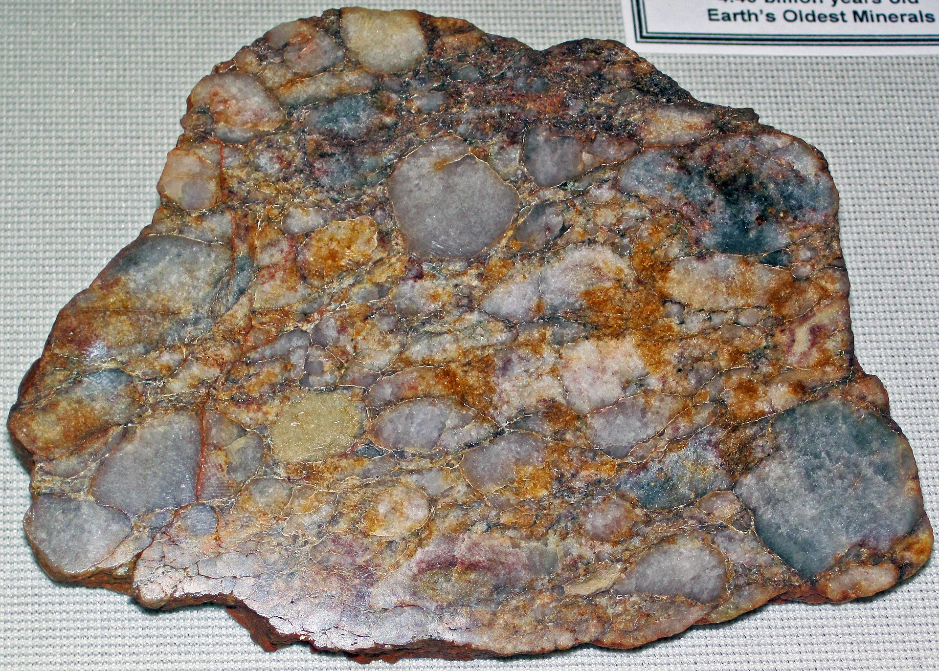 Quartz-pebble metaconglomerate (Jack Hills Quartzite), the rock type that contains the Earth's oldest dated mineral grains (detrital zircon). By: James St. John - Quartz-pebble metaconglomerate (Jack Hills Quartzite, Archean, 2.65 to 3.05 Ga; Jack Hills, Western Australia) CC BY 2.0