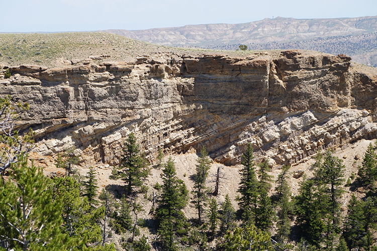Photograph showing horizontal conglomerate layers over tilted sandstone and mudstone layers, in an arid part of Wyoming.
