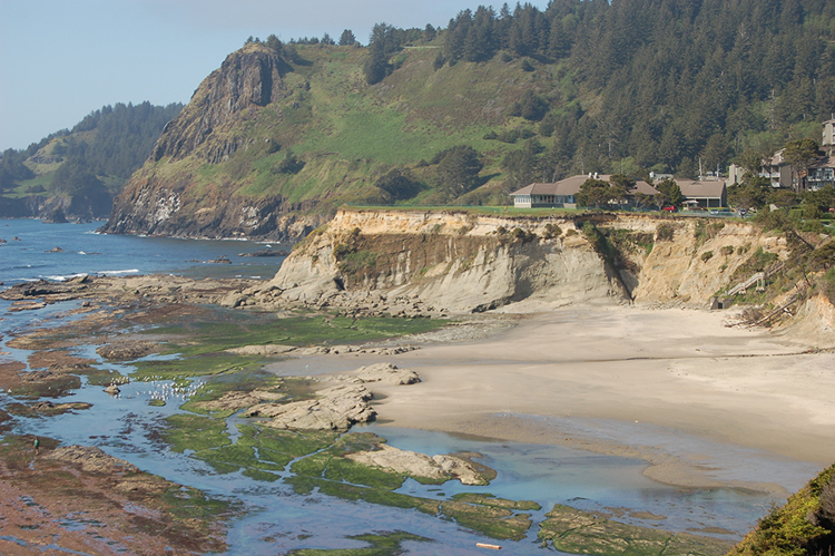 Photograph showing a seaside cliff exposure of tilted sedimentary layers truncating against horizontal sedimentary layers on the rugged Oregon coastline.