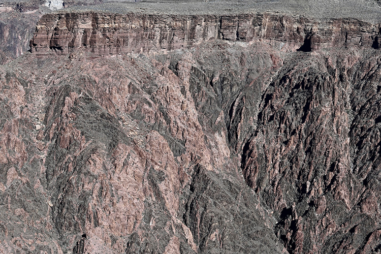 Photograph of a cliff in the Grand Canyon, with horizontal layers of sandstone overlying a massive, craggy slope of metamorphic and plutonic rocks.