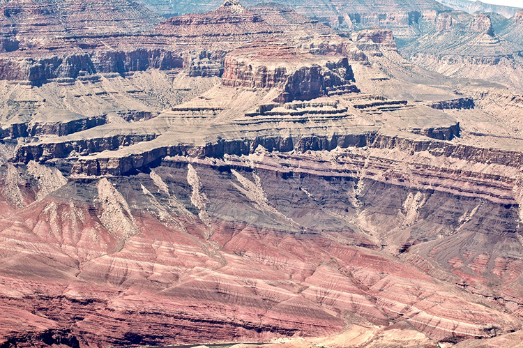 Landscape photo showing the angular contact between a lower package of tilted layers and an upper package of horizontal layers, all exposed in a dry desert canyon.