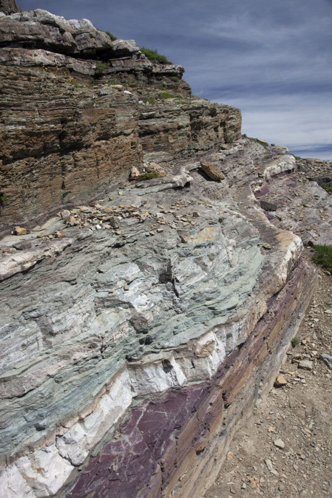 Brown, Green, white, and red sedimentary strata, indicating different levels of oxidation of disseminated iron in the rock. Proterozoic Spokane Formation, Glacier National Park, Montana.