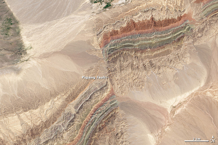 Satellite image of the Piqiang Fault, a northwest trending left-lateral strike-slip fault in the Taklamakan Desert south of the Tian Shan Mountains, China. NASA Earth Observatory images by Robert Simmon and Jesse Allen, using Landsat data from the USGS Earth Explorer. Public Domain.