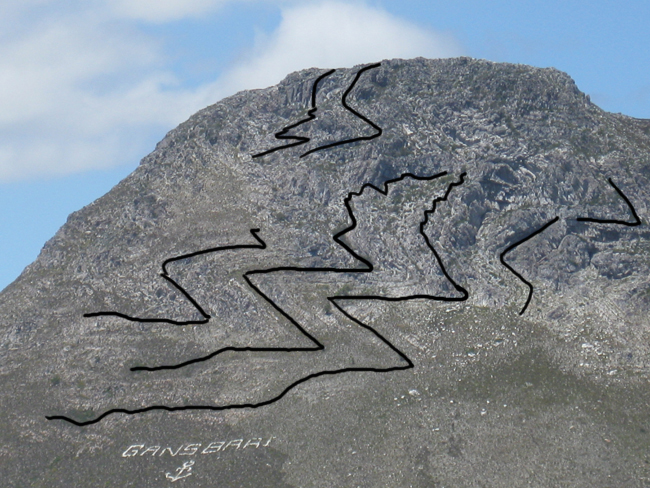 Annotated photograph showing the trace of bedding in crumpled up quartzites on the side of a mountain in south Africa. There is a blue sky beyond.