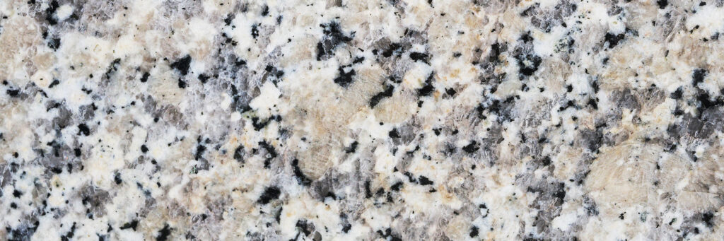 Close-up photo showing the phaneritic texture of a granite, with chunky crystals of quartz, two feldspars, and biotite. No sense of scale is provided, but the field of view is about 6 inches wide.